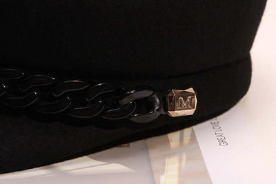 Black wool beret from BONEHEAD PRO-CREATIONS featuring a stylish chain and 'M' emblem, perfect for women.