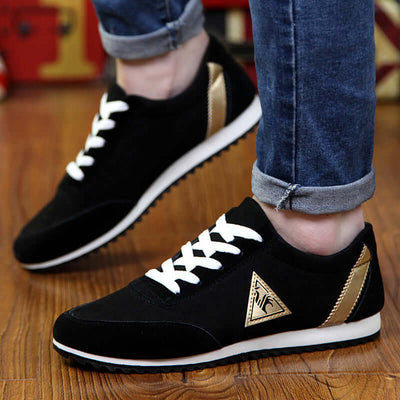 Stylish black sneakers with white laces and gold accents, perfect for casual wear.