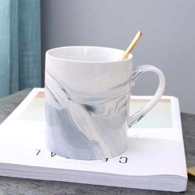 Elegant marble coffee mug made of ceramic, holding a golden spoon, ideal for daily use.