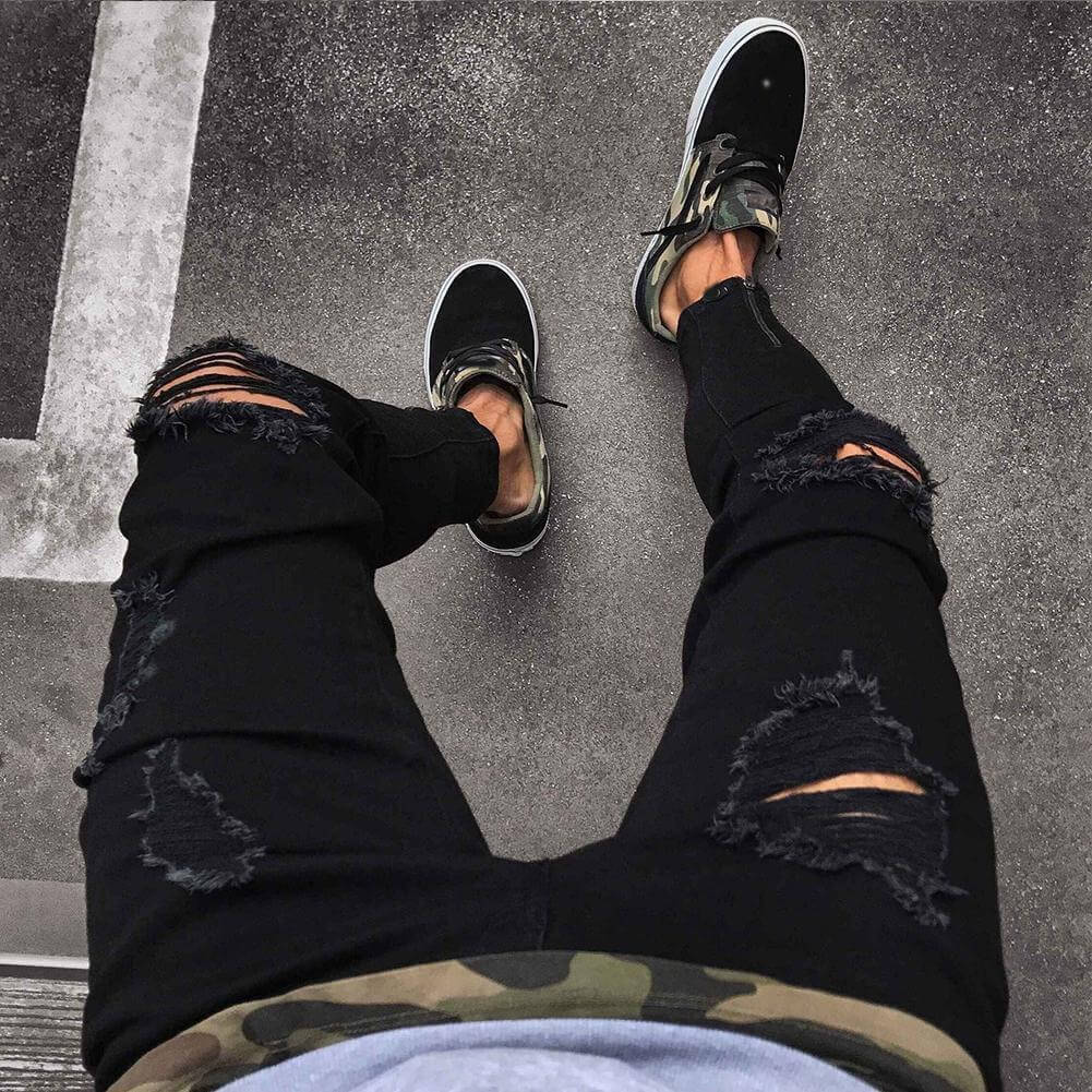Men's black ripped jeans with high elasticity, paired with stylish sneakers, perfect for casual wear.