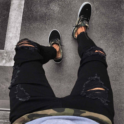 Men's black ripped jeans with high elasticity, paired with stylish sneakers, perfect for casual wear.