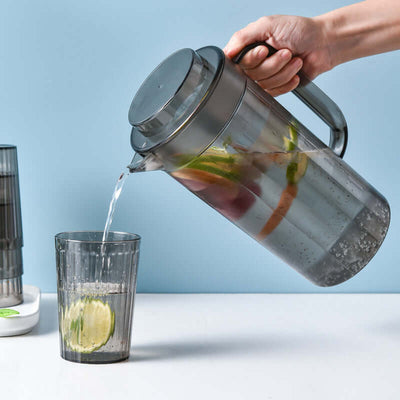 Modern black plastic cold water kettle pouring into a cup with fruit slices, perfect for refreshing drinks.