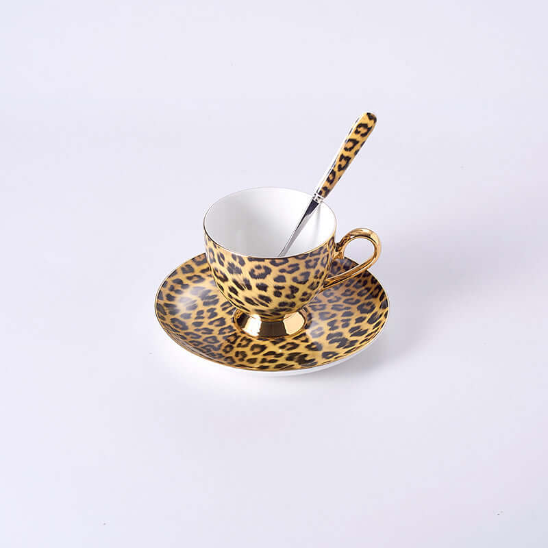 Leopard print porcelain coffee cup and saucer set with gold details and a matching spoon.