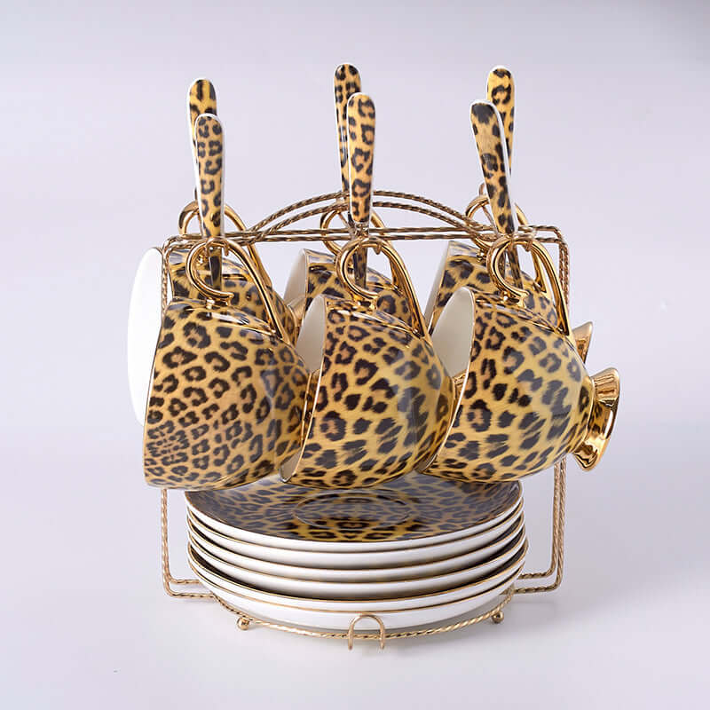 Leopard print porcelain coffee mugs with saucers and plates in a stylish gold holder.