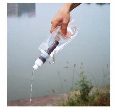Outdoor portable filter water bag being poured near a water body, showcasing its folding feature and practical design.