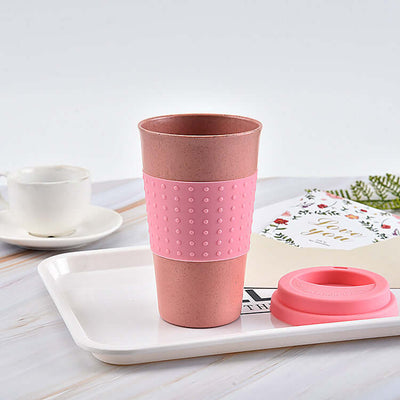 Biodegradable pink water cup made of wheat straw with silicone cap on a tray, perfect for tea or coffee.
