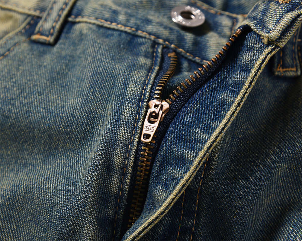 Close-up of dark blue denim jeans zipper showcasing quality craftsmanship for men's fashion work clothes.