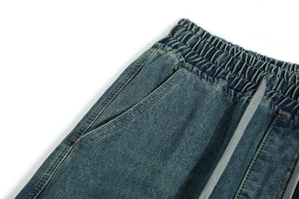 Close-up view of men's denim trousers featuring an elastic waistband and side pockets in blue.