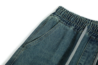 Close-up view of men's denim trousers featuring an elastic waistband and side pockets in blue.