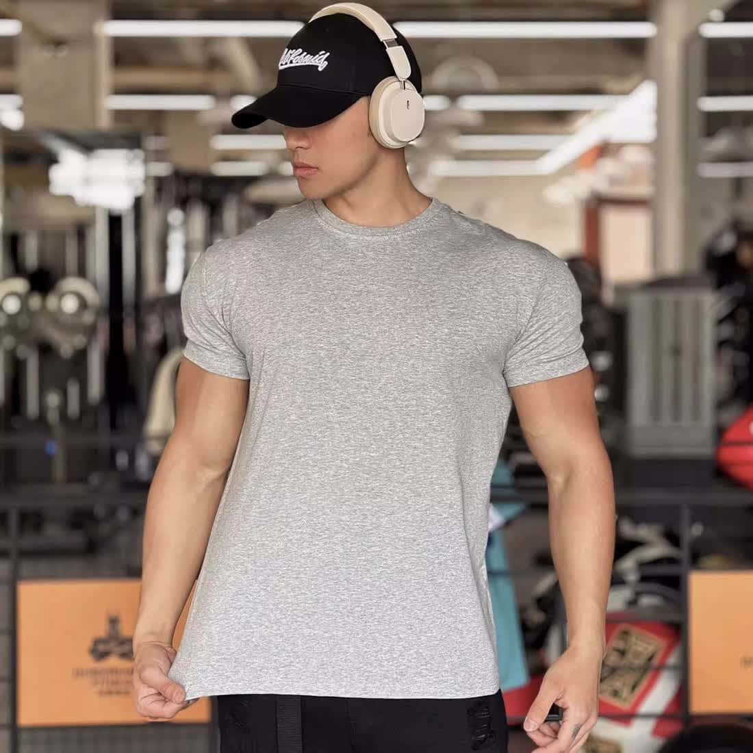 Men's slim fit grey short-sleeved sports t-shirt, ideal for summer fitness, shown in a gym setting.