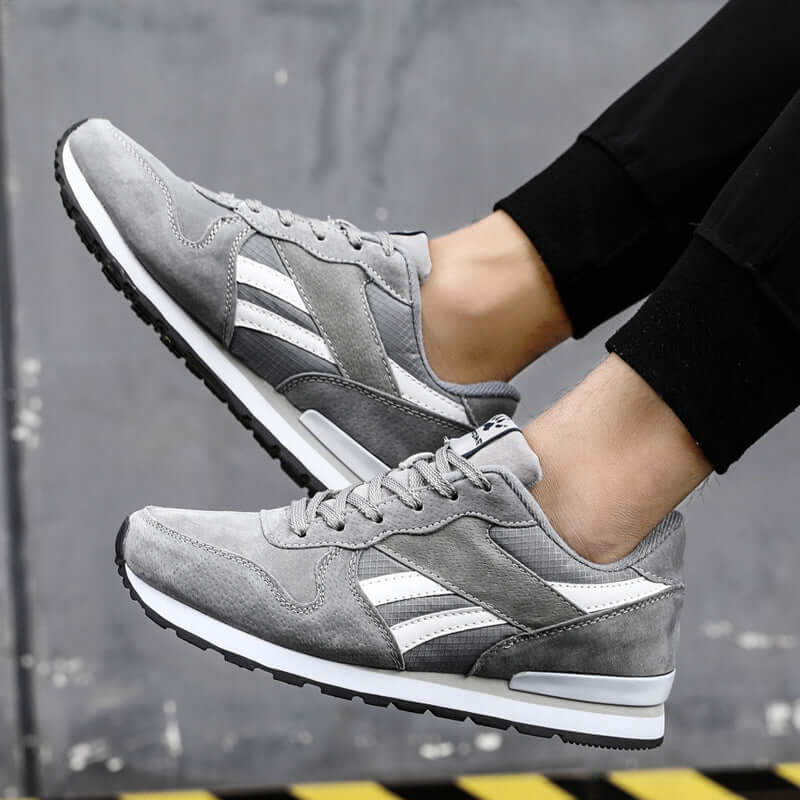Men's casual gray running shoes with white stripes, featuring mesh and rubber sole, perfect for everyday wear.