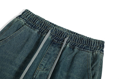 Close-up of denim trousers waistband for men, featuring elastic band and drawstrings in blue fabric.