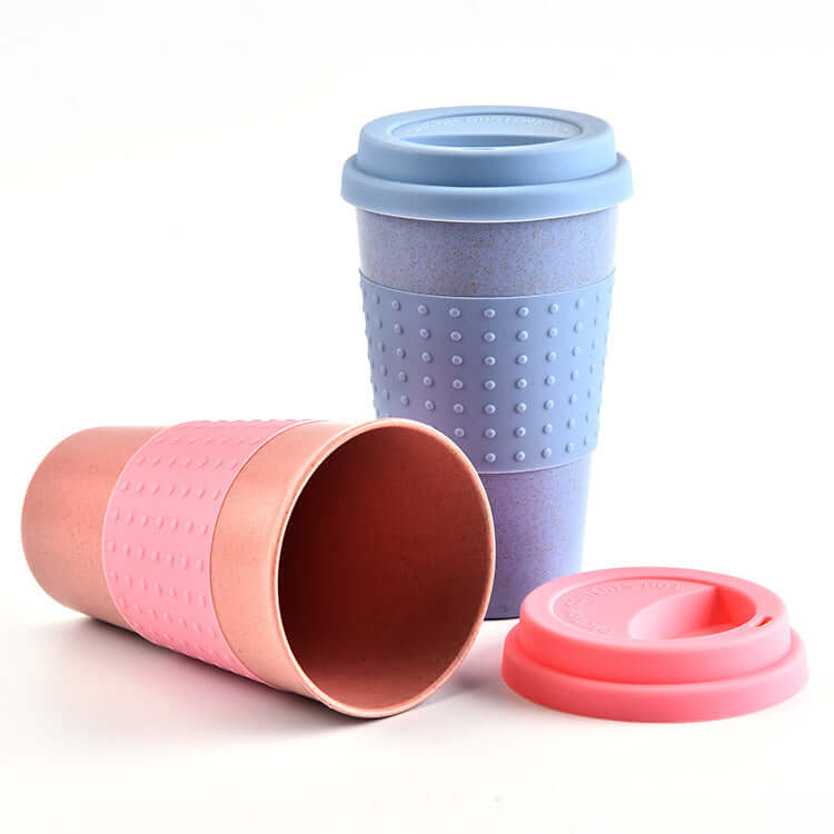 Colorful biodegradable water cups made from wheat straw with silicone caps in pink and blue.