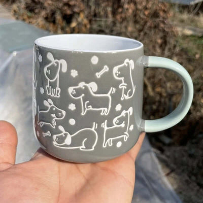 Gray ceramic mug featuring playful dog designs and a comfortable handle, perfect for pet lovers.