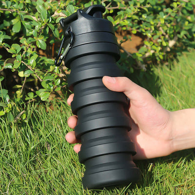 Collapsible black water bottle held in hand, perfect for outdoor activities, BPA-free and durable design.