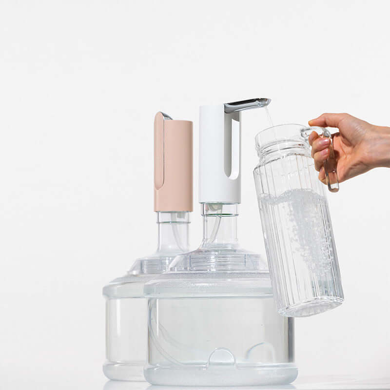 Electric household mineral water dispenser with water outlet pump in use, filling a jug from a large water bottle.