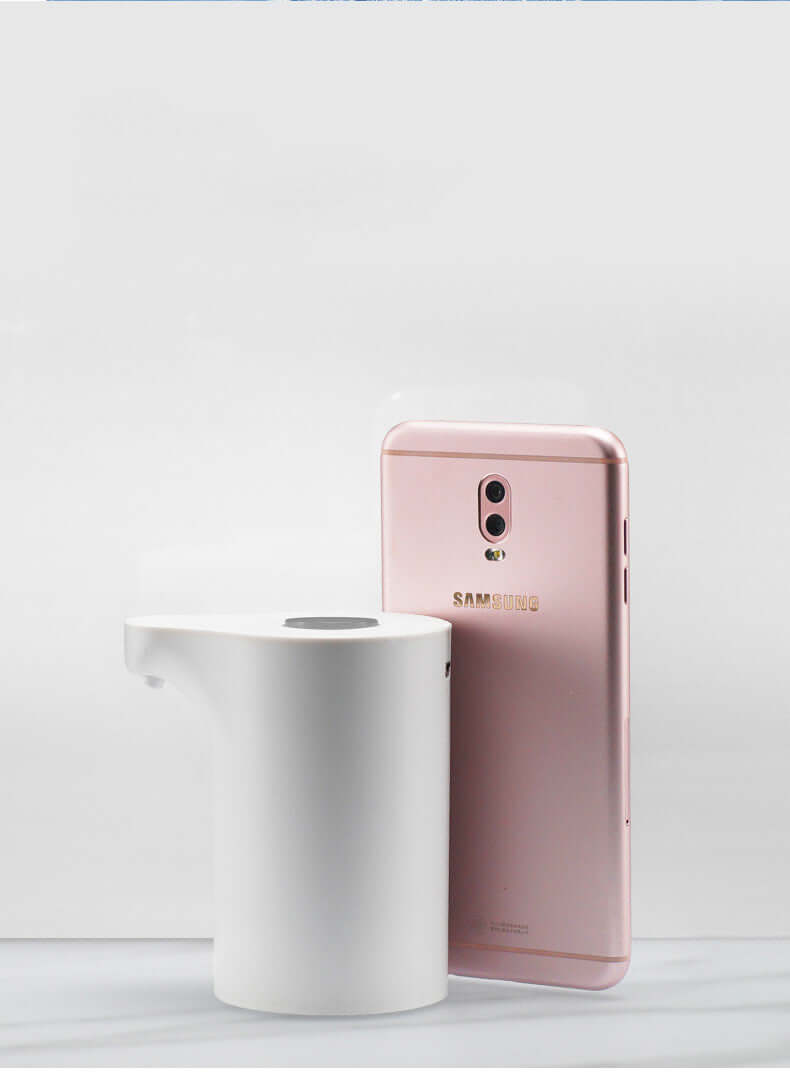 Electric water pump in white beside a rose gold smartphone on a plain background.