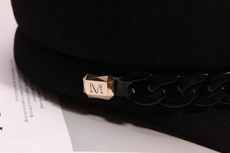 Close-up of women's high-end wool baseball cap with decorative chain and M clasp, featuring a wide brim.
