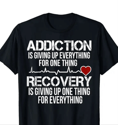 Black tee shirt with bold text on addiction and recovery, featuring heartbeat and heart graphics.