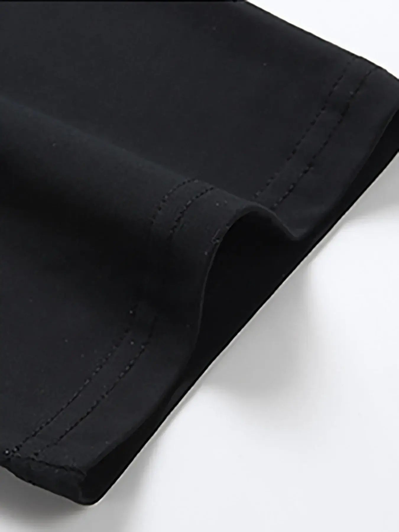 Close-up of black cotton fabric showcasing stitching details of the Cotton Flag Print Tee by BONEHEAD PRO-CREATIONS.