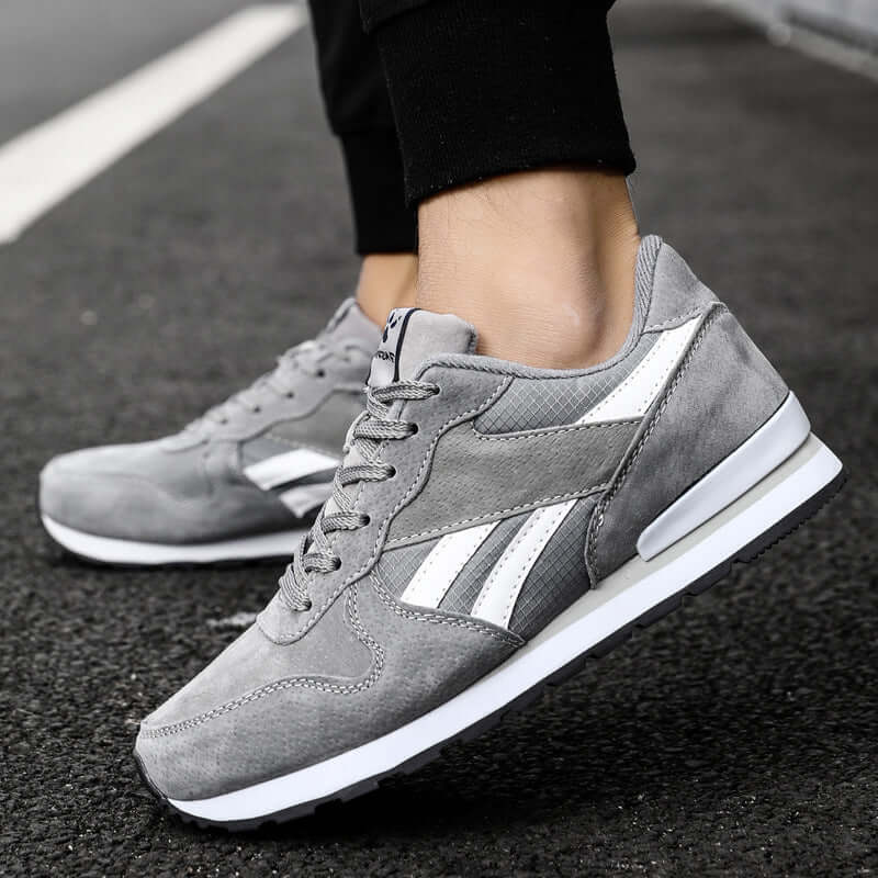Casual men's running shoes in gray and white, featuring a low profile and rubber sole for comfortable wear.