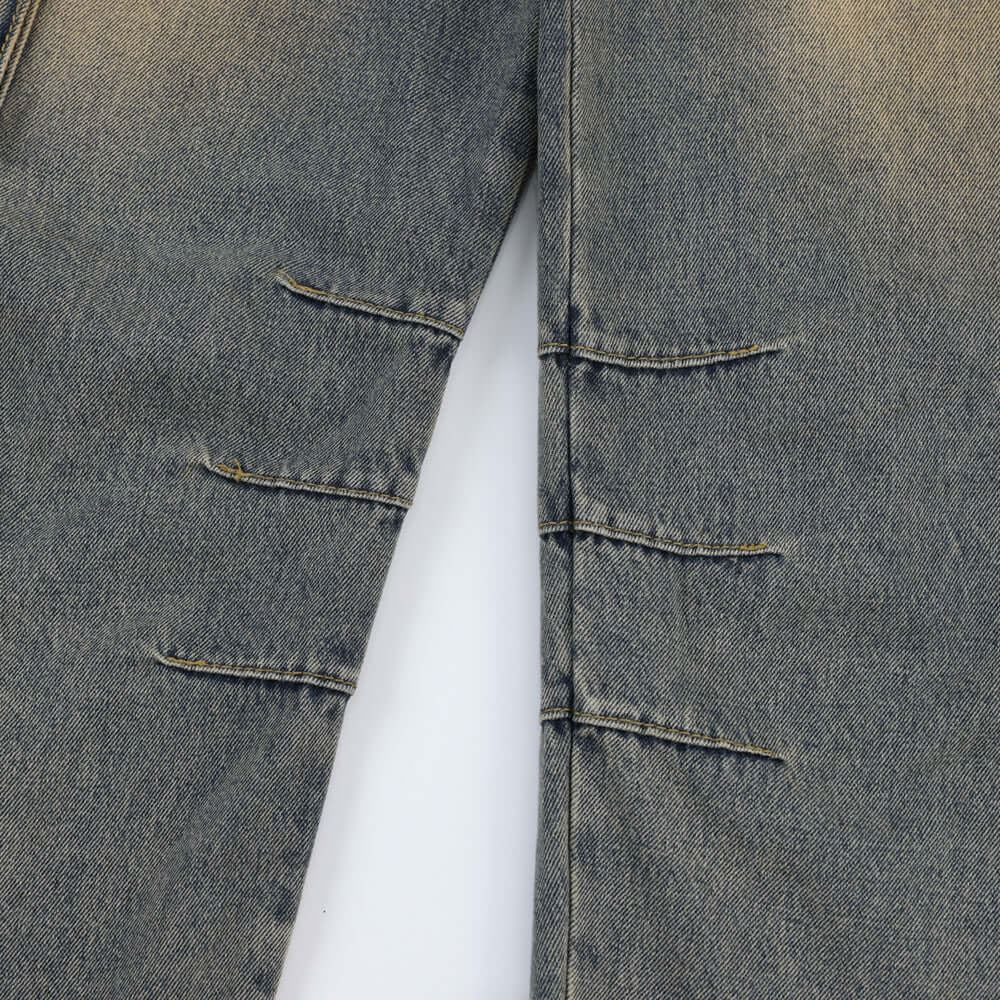 Close-up of vintage blue denim jeans for men featuring distressed design and unique stitching details.