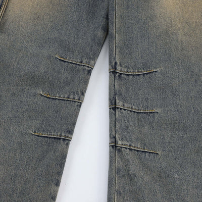 Close-up of vintage blue denim jeans for men featuring distressed design and unique stitching details.