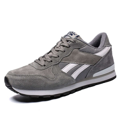 Gray casual running shoes with white stripes, ideal for men, featuring a stylish low upper and comfortable sole.