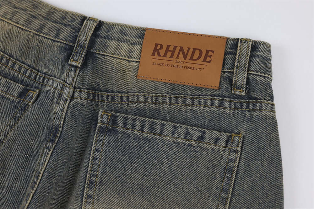 Close-up of vintage denim jeans for men featuring a branded leather patch on the back waistband.