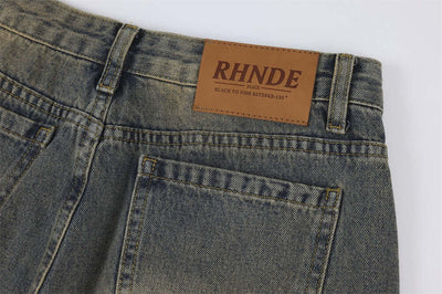 Close-up of vintage denim jeans for men featuring a branded leather patch on the back waistband.