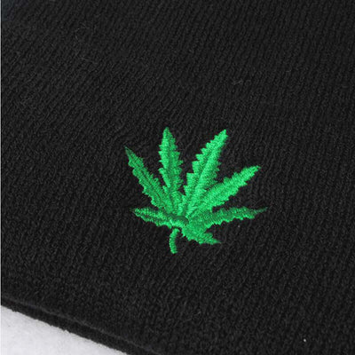 Close-up of a black knitted hat featuring a vibrant green embroidered maple leaf design by BONEHEAD PRO-CREATIONS.