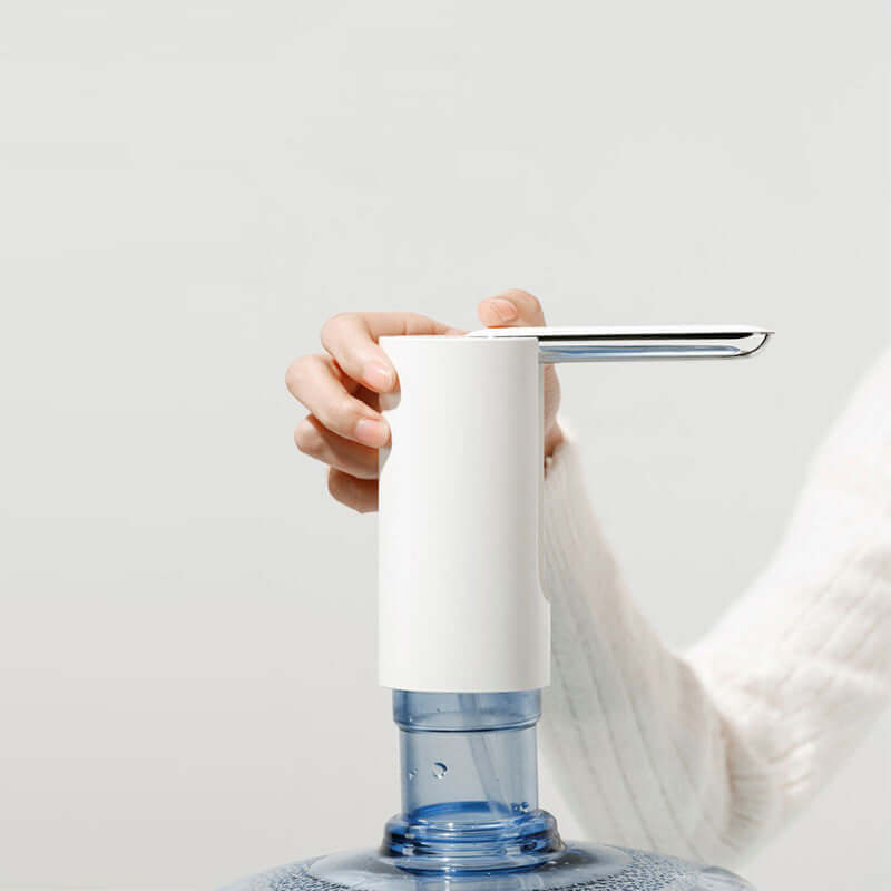 White electric water dispenser pump in use with a water barrel.